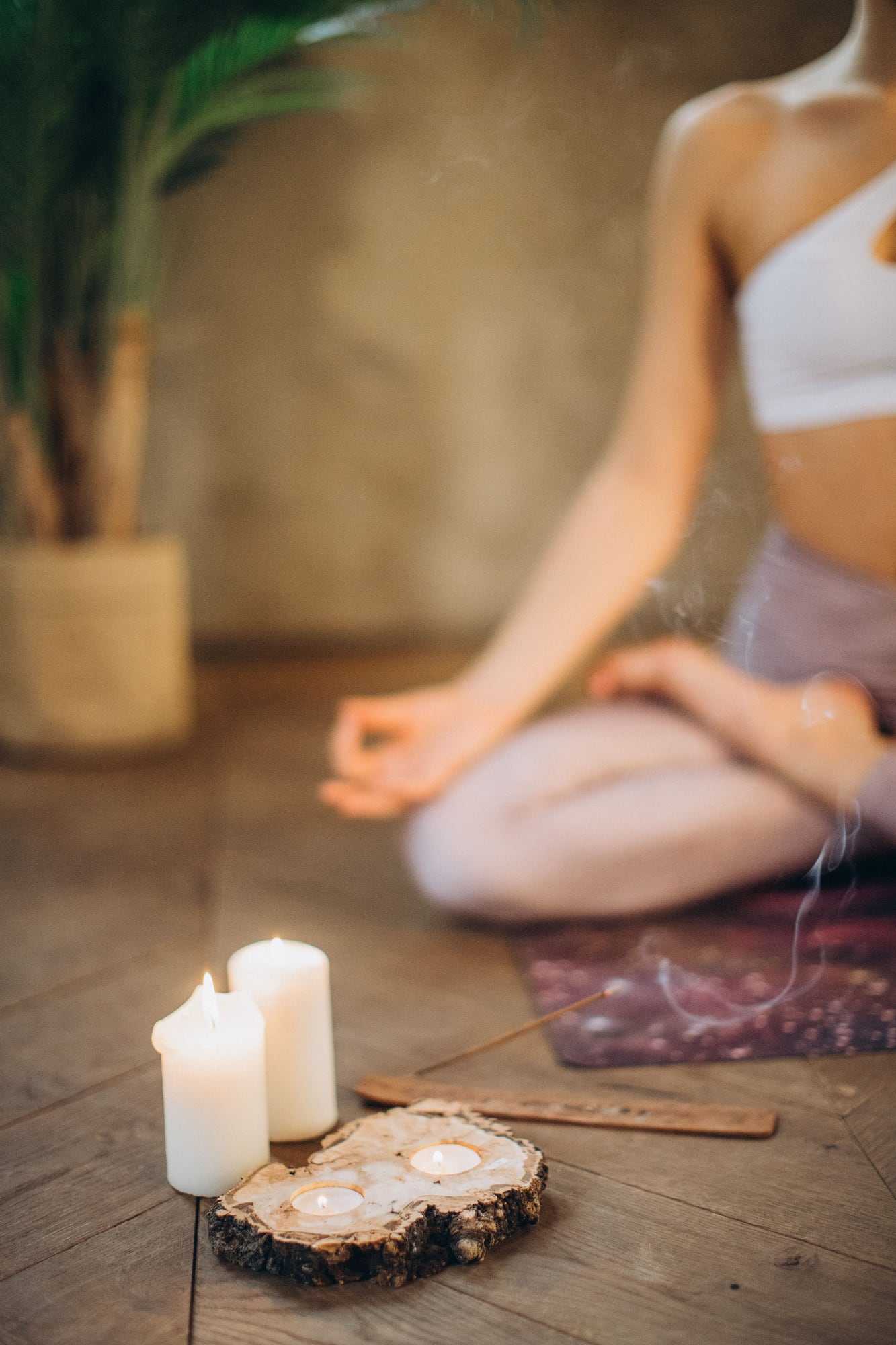 Candles on a wooden floor beside a person sitting cross-legged