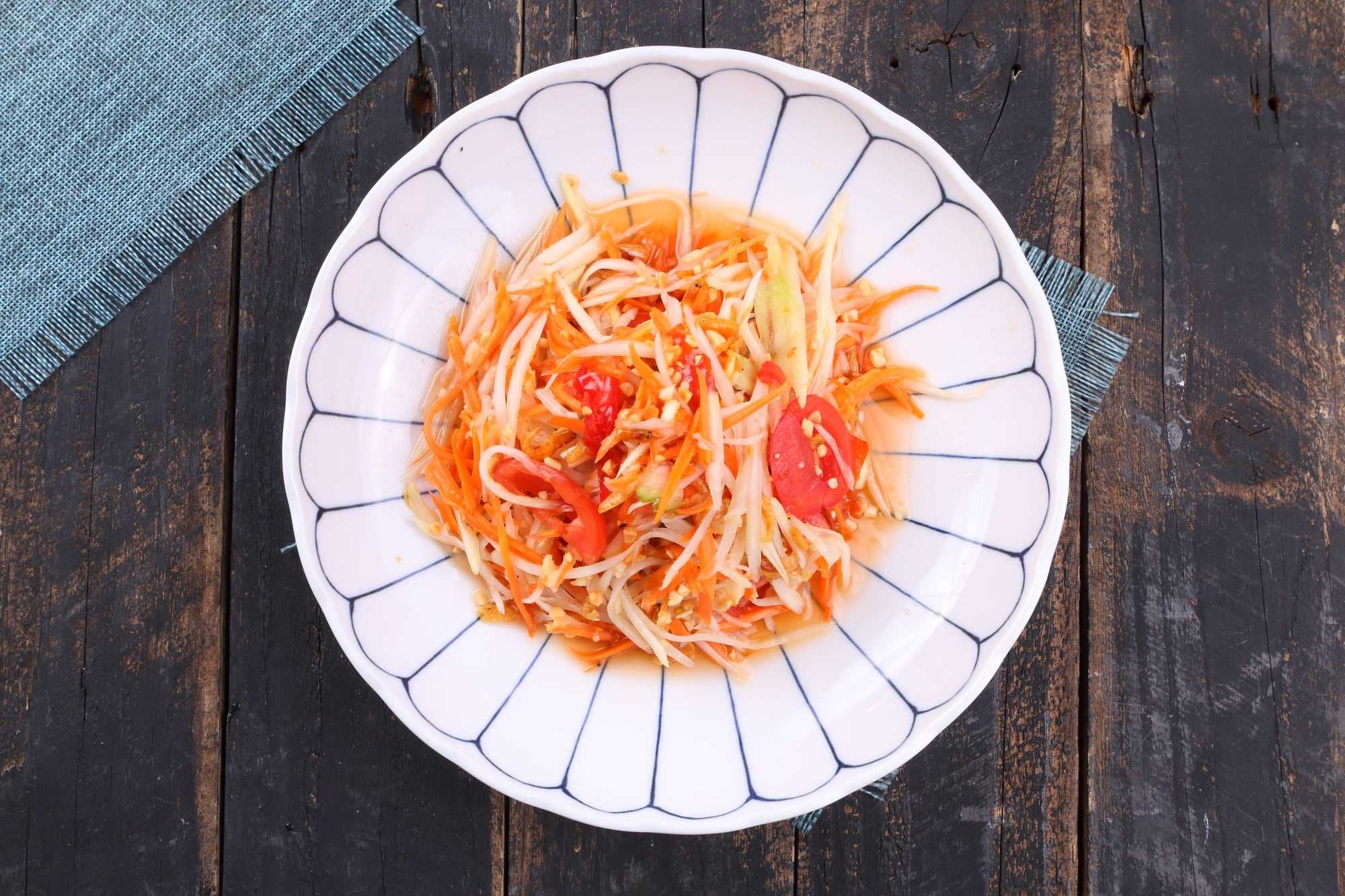A plate of green papaya salad on a dark wooden table