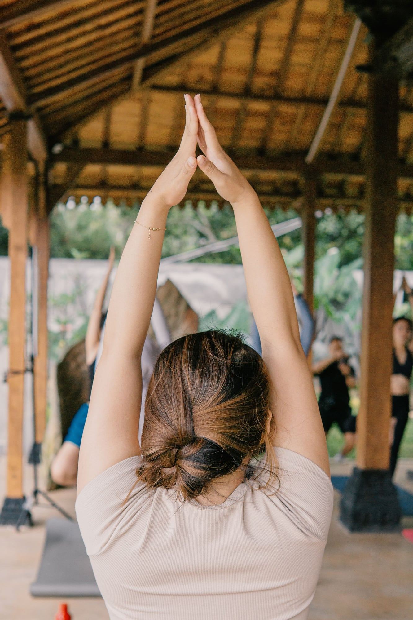 An open-air yoga class in a wooden pavilion, seen from behind